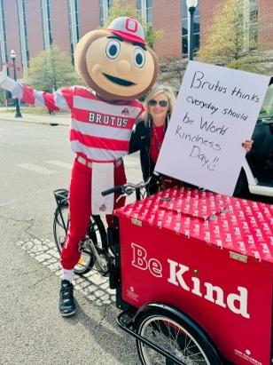 Brutus holding a kindness sign on a bike