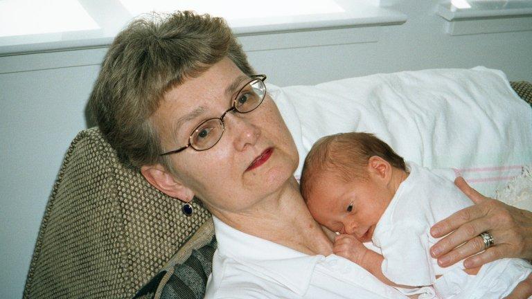 Nurse Martha Pitzer holds an infant on her chest