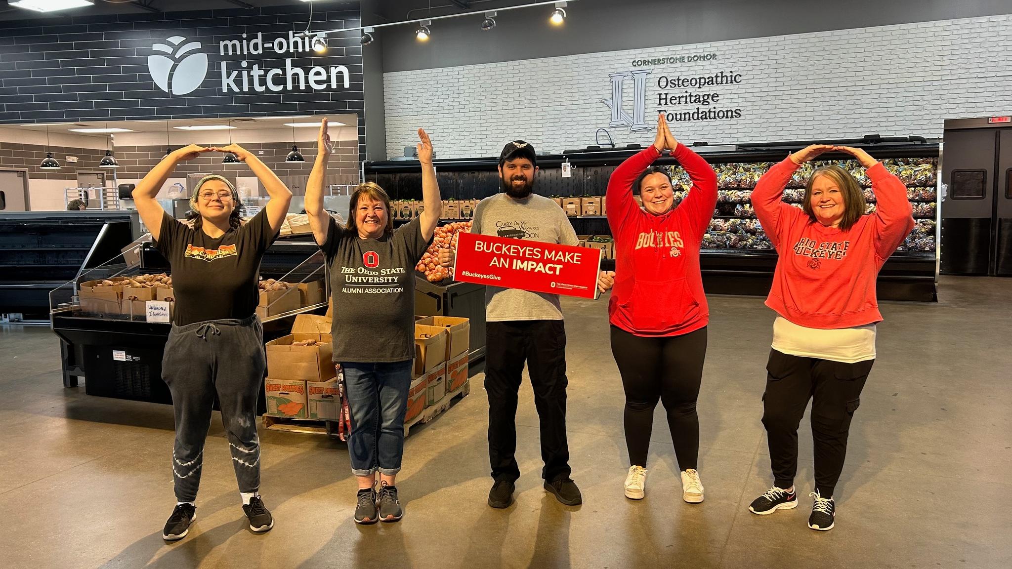 four buckeyes pose for an o-h-i-o photo inside the mid-ohio food kitchen