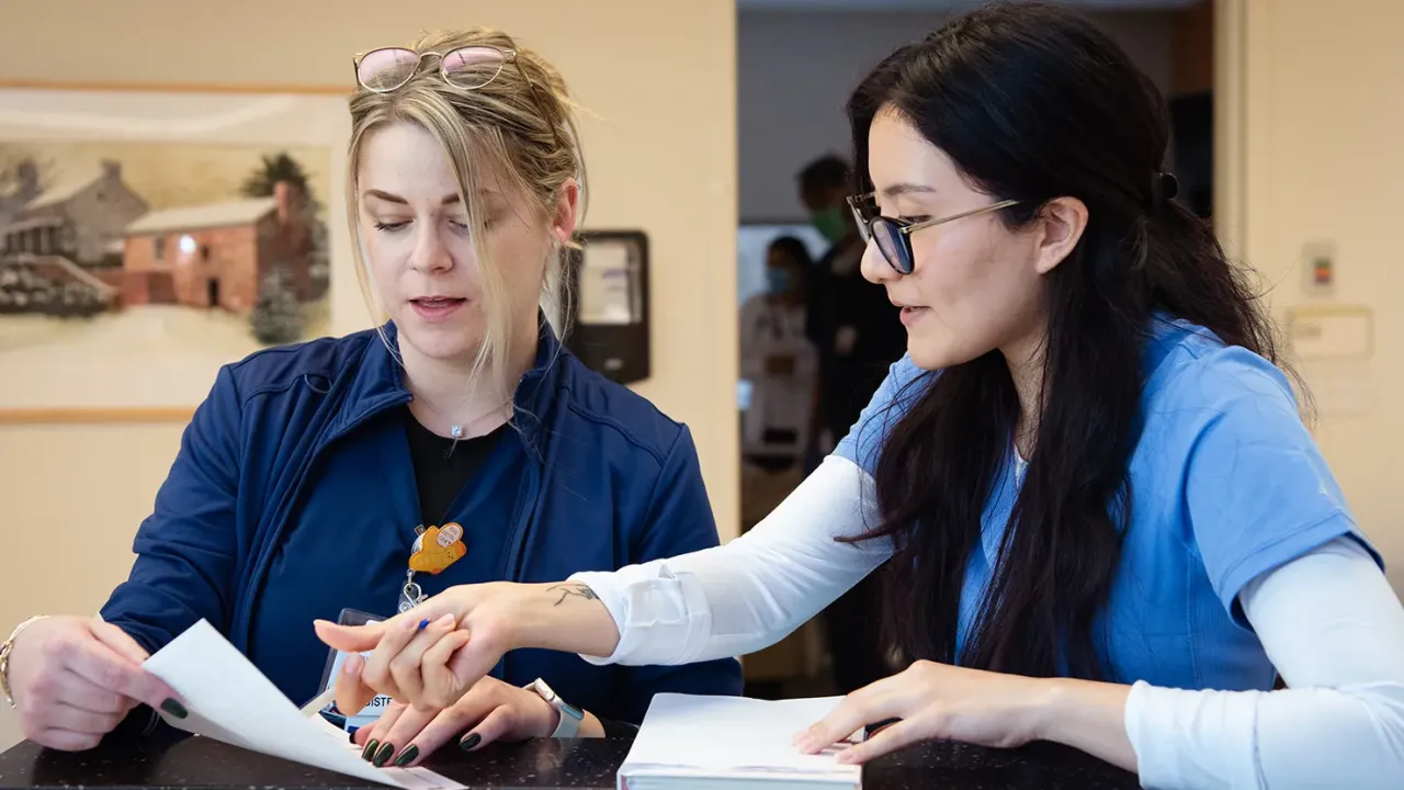 two women pointing to a paper and discussing its content
