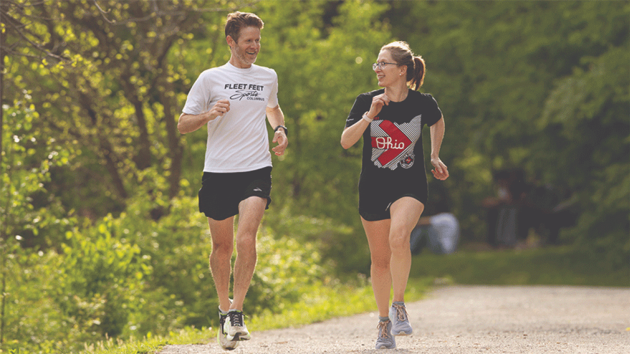 Ohio State oncologist Mary Dillhoff and her friend Michael Patton run at Antrim Park in north Columbus. They plan to run 75 miles together during Pelotonia Ride Weekend Aug. 2–3. (Photo by Jodi Miller)